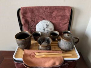 Tea set for brewing includes tea pot, strainer, 4 tea cups, serving cup and tea tongs and white tea.